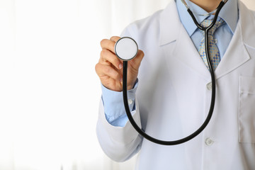Doctor in medical gown with black stethoscope, space for text