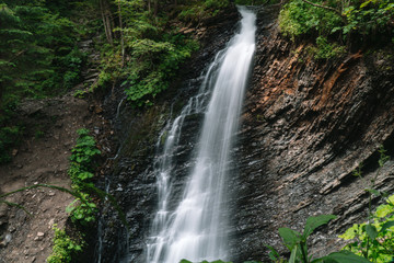 Fototapeta na wymiar Beautiful waterfall in summer. A fast waterfall. View of the waterfall from below