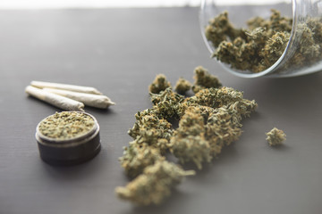 joint with weed, Cannabis buds on black table, grinder with fresh marijuana, top view close up,...