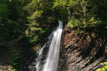 Fototapeta na wymiar Beautiful waterfall in summer. A fast waterfall. View of the waterfall from below