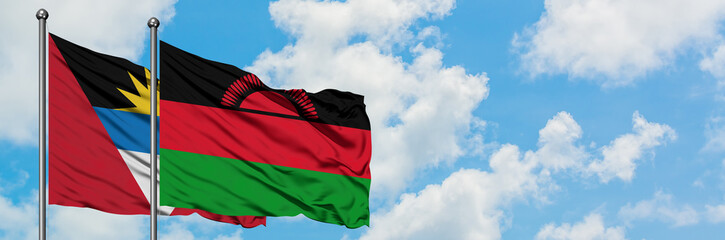 Antigua and Barbuda with Malawi flag waving in the wind against white cloudy blue sky together. Diplomacy concept, international relations.