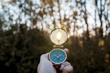 Closeup shot of a person holding a compass with the sun shining through the hole