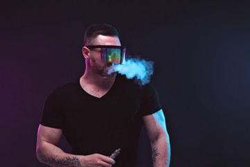 Men with beard in sunglasses vaping and releases a cloud of vapor.