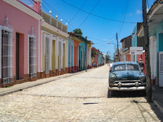 Old car parked in front of colorful houses on the cobblestone streets of the UNESCO World Heritage old town in Trinidad, Cuba
