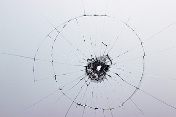 Shot, broken glass, fragments. Hole in the window. Cracks on transparent material. Cracked glass on a white background texture.