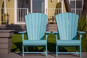 Bright blue Adirondack plastic chairs in the Oregon Coast; vacation and seaside mood.