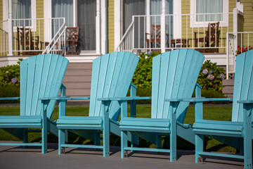 Fototapeta na wymiar Bright blue Adirondack plastic chairs in the Oregon Coast; vacation and seaside mood.