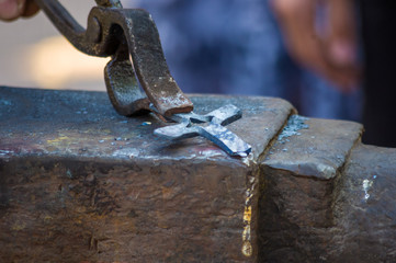 blacksmith performs the forging of hot glowing metal on the anvil