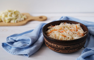 Pickled cabbage with carrot in ceramic bowl. Homemade preserving. Russian traditional fermented food.