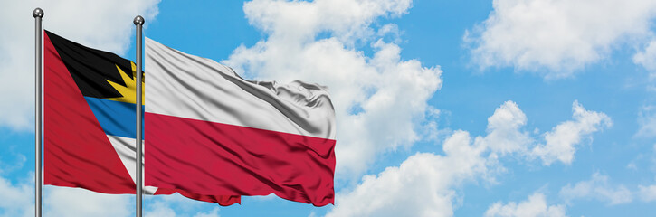 Antigua and Barbuda with Poland flag waving in the wind against white cloudy blue sky together. Diplomacy concept, international relations.
