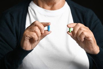 Elderly woman with pills on dark background, closeup