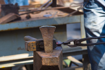 blacksmith performs the forging of hot glowing metal on the anvil