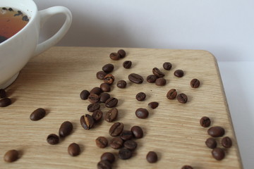 whole Arabica coffee beans and a Cup of coffee on a Board with a white background