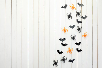 halloween, decoration and scary concept. Black paper bats and spiders on white wooden background