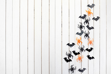 halloween, decoration and scary concept. Black paper bats and spiders on white wooden background