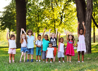 many young children of different races play together in the Park on the green fresh grass. The...