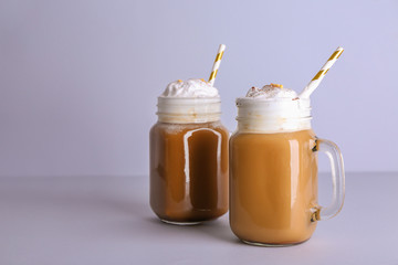 Mason jars of tasty frappe coffee on grey background