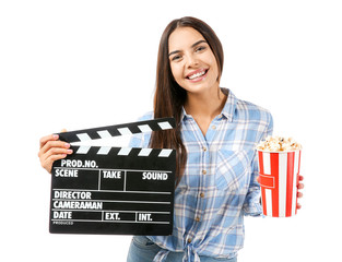 Young woman with popcorn and movie clapper on white background