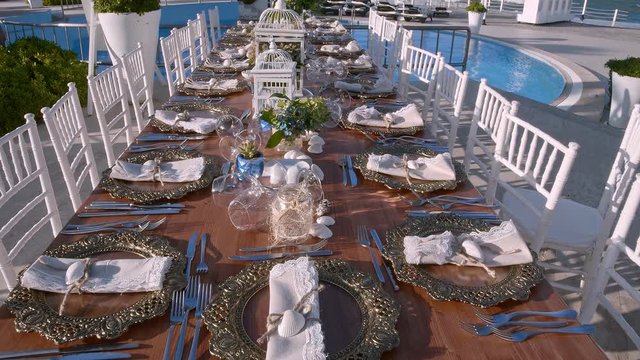 Decorated Wedding Tables is a stock video that consists of gorgeous footage of beautifully decorated wedding tables arrange near the swimming pool and sea. The place looks like a high-end wedding venu
