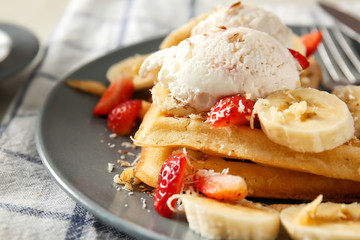 Tasty waffles, ice cream and fruits on plate, closeup