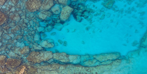 An aerial view of the beautiful Mediterranean sea, where you can se the rocky textured underwater corals and the clean turquoise water of blue lagoon Agia Napa