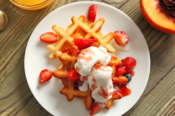 Plate with tasty waffles, ice cream and berries on table