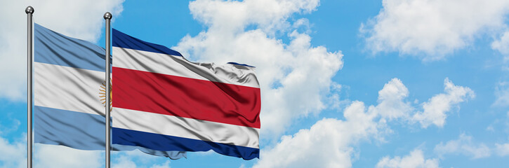 Argentina and Costa Rica flag waving in the wind against white cloudy blue sky together. Diplomacy concept, international relations.