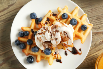 Plate with tasty waffles, ice cream and berries on table