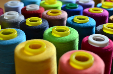 Background of bobbins with multicolored threads for sewing. Needlework, sewing and tailoring concept. Fabric and textile industry