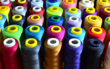 Background of bobbins with multicolored threads for sewing. Needlework, sewing and tailoring...