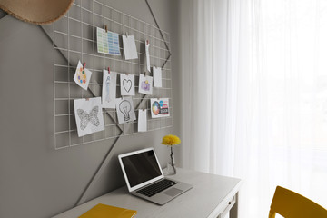 Comfortable workplace with mood board and laptop near grey wall