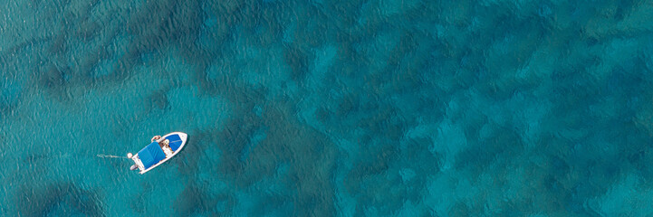 An aerial view of a boat in the beautiful Mediterranean sea, where you can se the rocky textured...