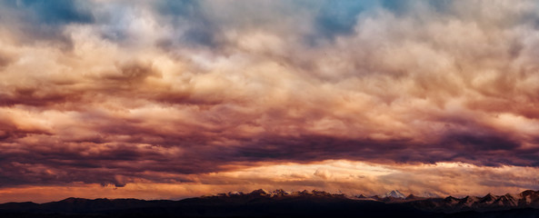 Dramatic light through the clouds against the backdrop of an exciting, vibrant stormy sky at sunset, dawn in the mountains. panorama, natural composition