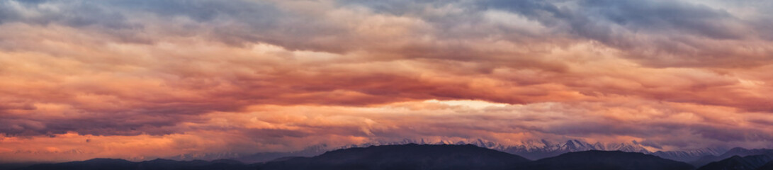 Dramatic light through the clouds against the backdrop of an exciting, vibrant stormy sky at sunset, dawn in the mountains. panorama, natural composition