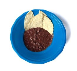 refried black beans with corn tortilla on blue bowl with white background. typical food of Guatemala
