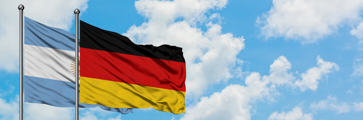 Argentina and Germany flag waving in the wind against white cloudy blue sky together. Diplomacy concept, international relations.