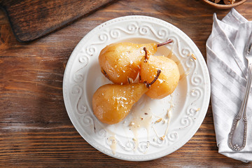 Plate with tasty cooked pears on table