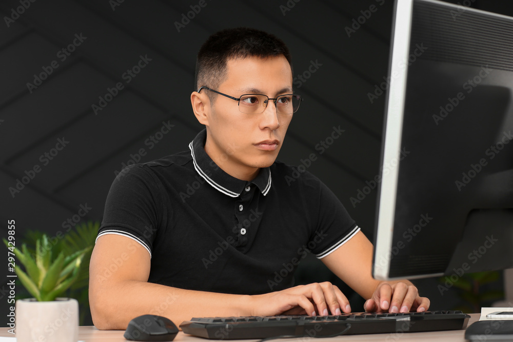 Poster asian programmer working on computer in office