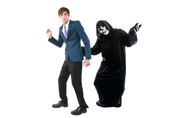Man in a Halloween grim reaper ghost costume chasing, mocking and making fun of scared businessman...