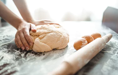 Gordijnen Het maken van deeg door vrouwelijke handen op houten tafel achtergrond. Koken concept. Mooie vrouwelijke handen. © maxbelchenko