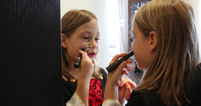 blonde six years old girl preparing for Halloween, painting her face looking at mirror in corridor inside home. 4k