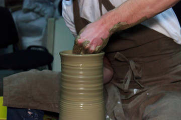 experienced potter makes a large vase on a potter's wheel. clay product. hands of a potter. reportage shooting.