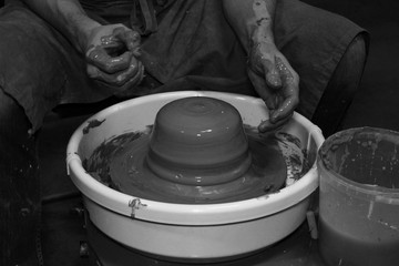 experienced potter makes a large vase on a potter's wheel. twisting a narrow neck. clay product. hands potter. reportage shooting. work with large piece of clay