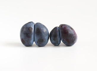 Trendy ugly food concept. Two purple plums on a white background. Fruit with a strange shape. The...
