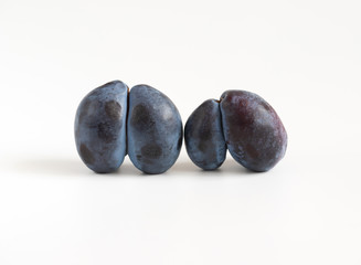 Trendy ugly food concept. Two purple plums on a white background. Fruit with a strange shape. The problem of food waste