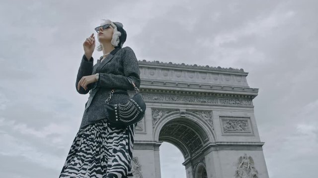 Outdoor autumn fashion portrait of elegant, luxury lady wearing trendy boucle blazer, animal, zebra print pleated midi skirt, holding baguette bag, posing near Triumphal Arch in Paris
