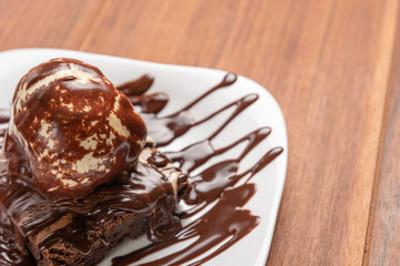 Chocolate Brownie with Vanilla Ice Cream and chocolatel syrup isolated on wooden background