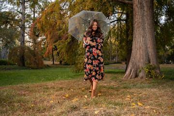 Elegant woman with transparent umbrella walking in park / nature 