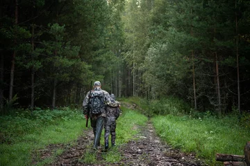 Rolgordijnen vader wijst en begeleidt zoon op eerste hertenjacht © romankosolapov