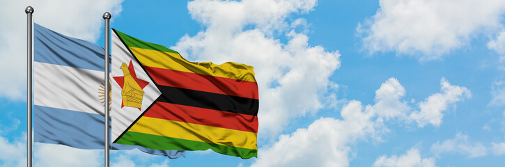 Argentina and Zimbabwe flag waving in the wind against white cloudy blue sky together. Diplomacy concept, international relations.